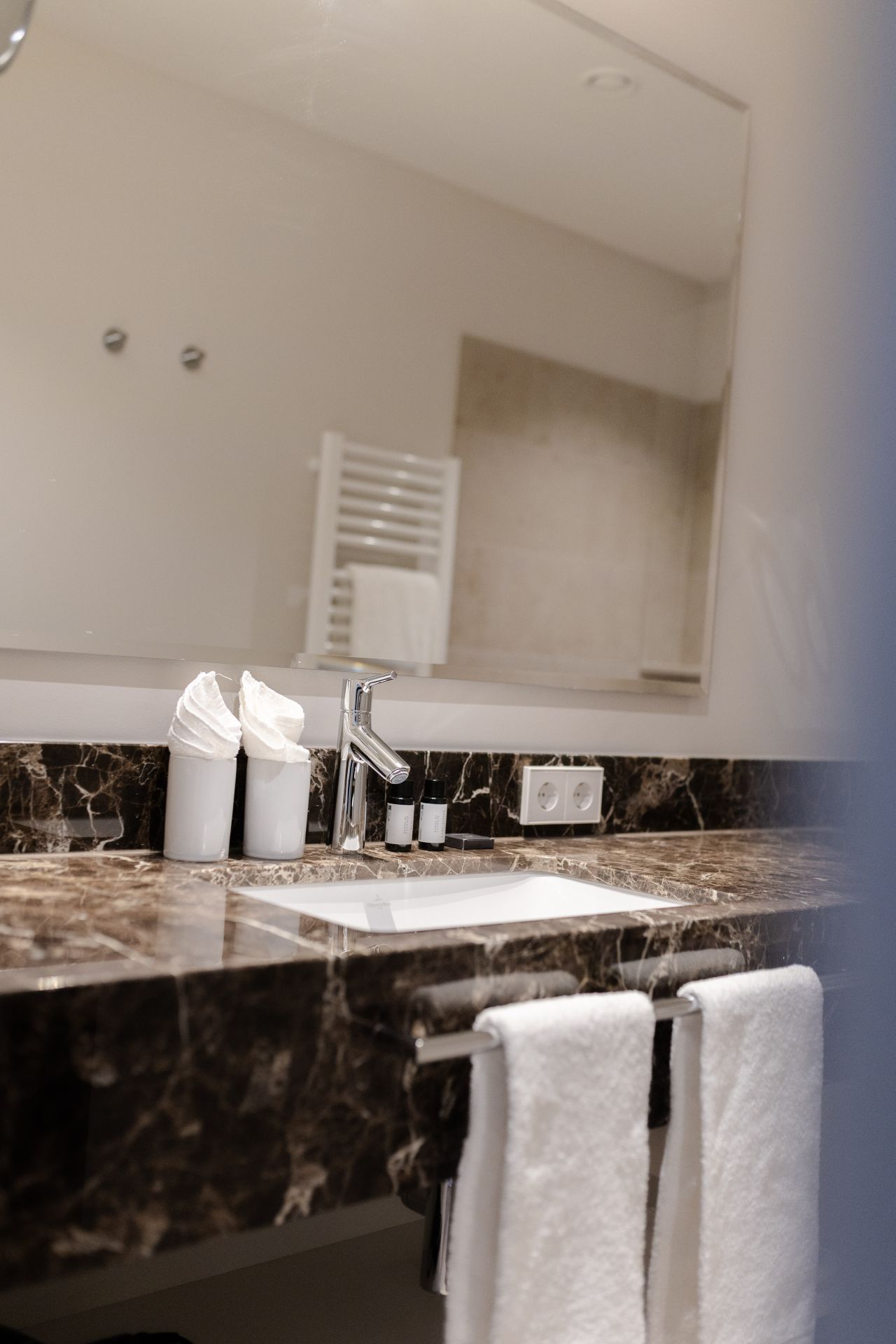 Renoviertes Hotelbad mit Naturstein-Waschtisch und modernen Armaturen im historischen Gebäude