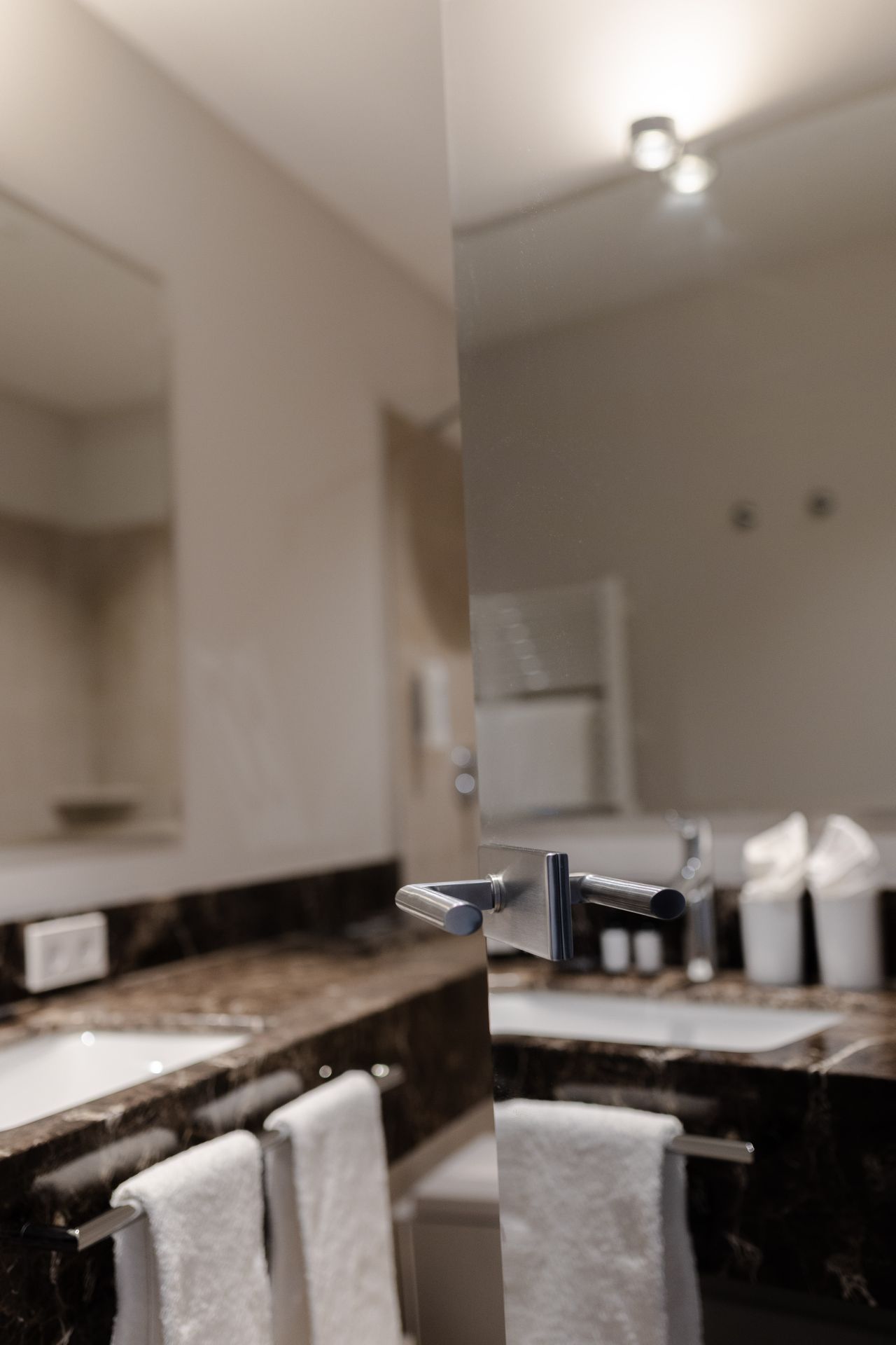 Detailansicht eines erneuerten Hotelbads mit Spiegel, Armaturen und Naturstein