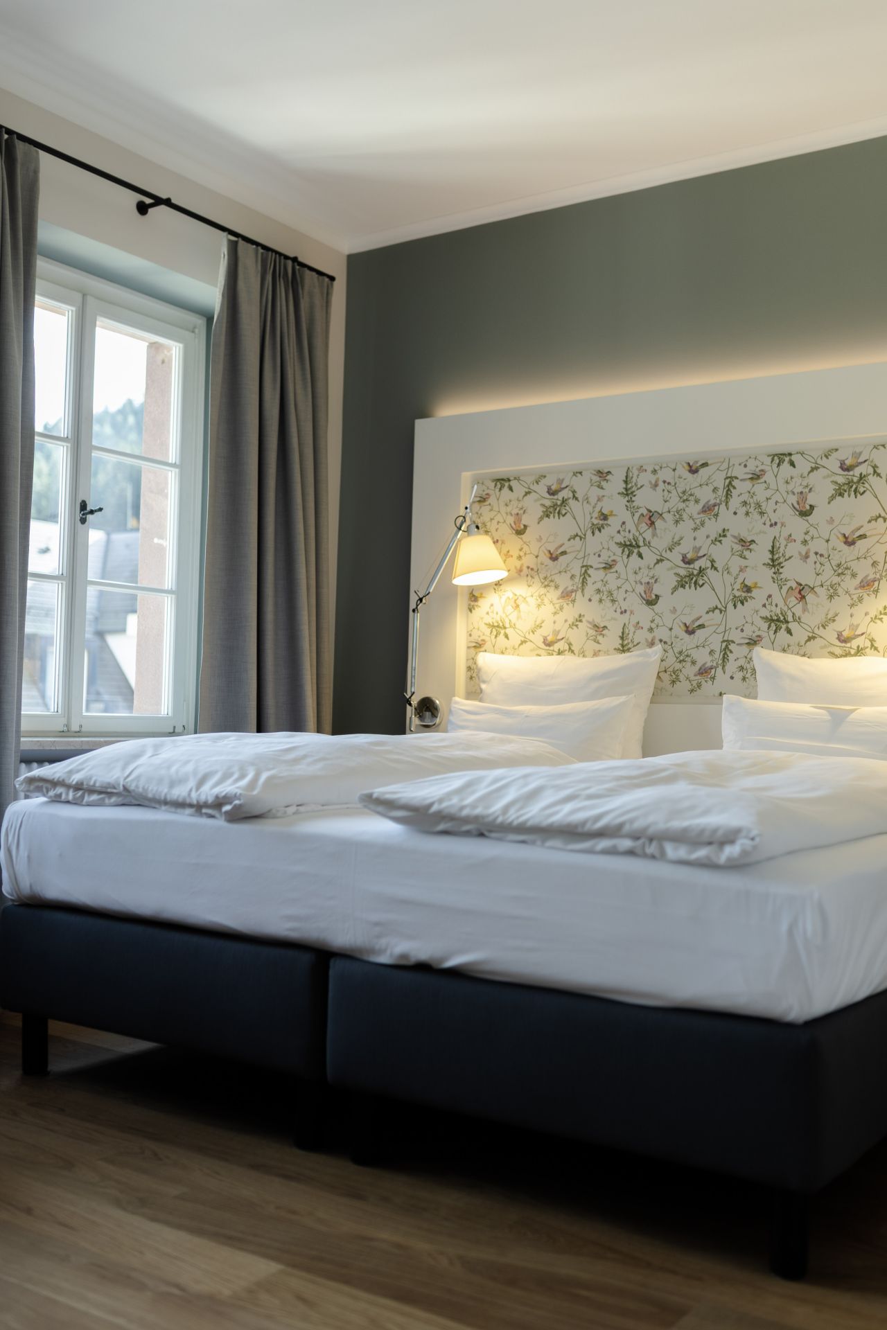 Sanierter Hotelzimmerbereich im historischen Gebäude mit maßgefertigtem Kopfteil und warmem Licht