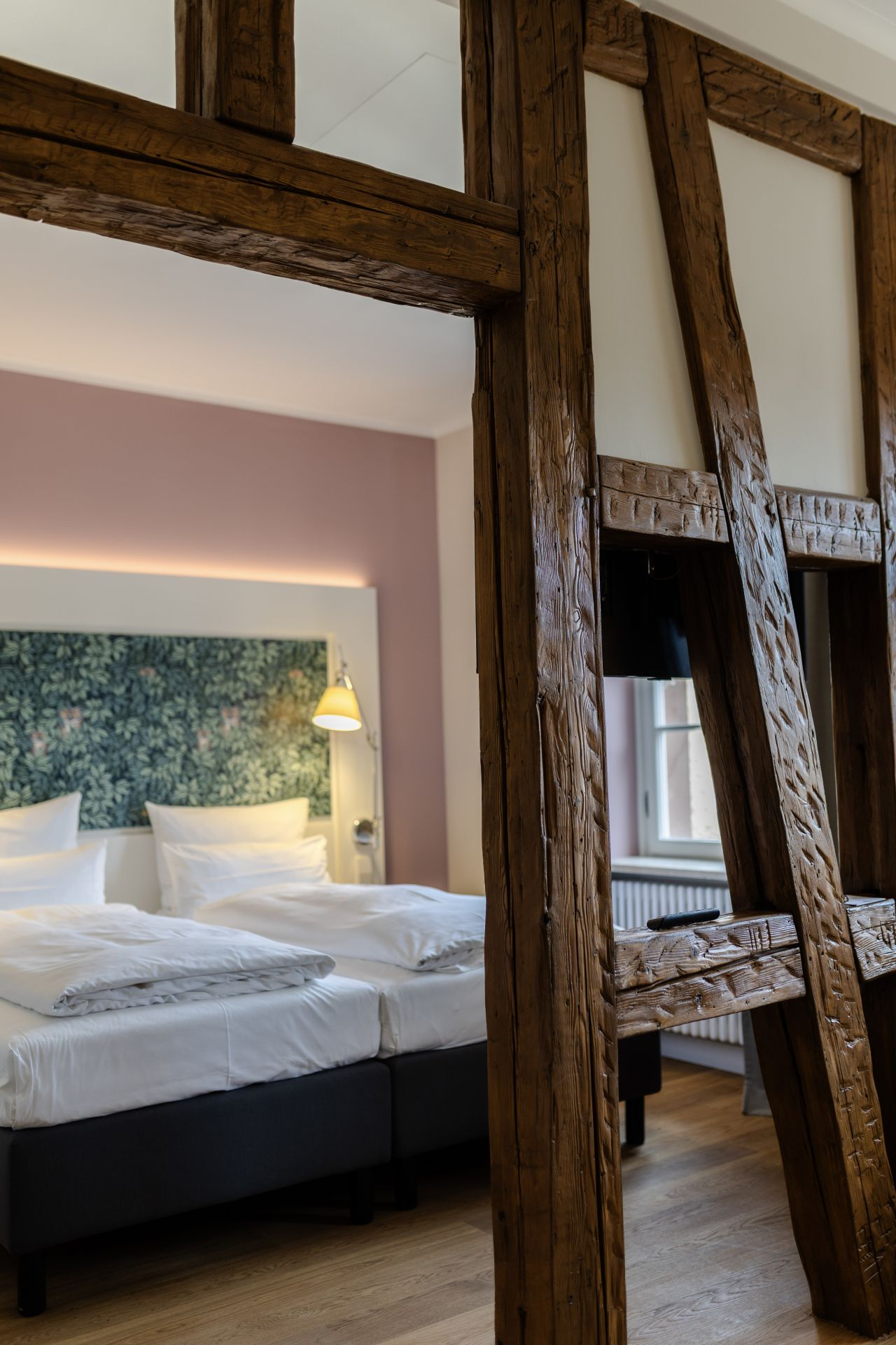 Überarbeitetes Hotelzimmer mit sichtbarer Holzkonstruktion und eleganter Möblierung